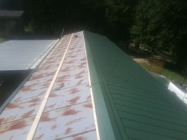 Old rusted panels beside newly installed green metal roofing — Wind Damage Roof Repair by Roofing Brothers in Pleasant View