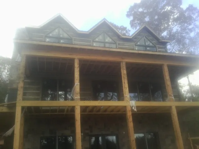 Dormers and porch framing on a large log home under construction — Roof Coating work by our crew in Pleasant View