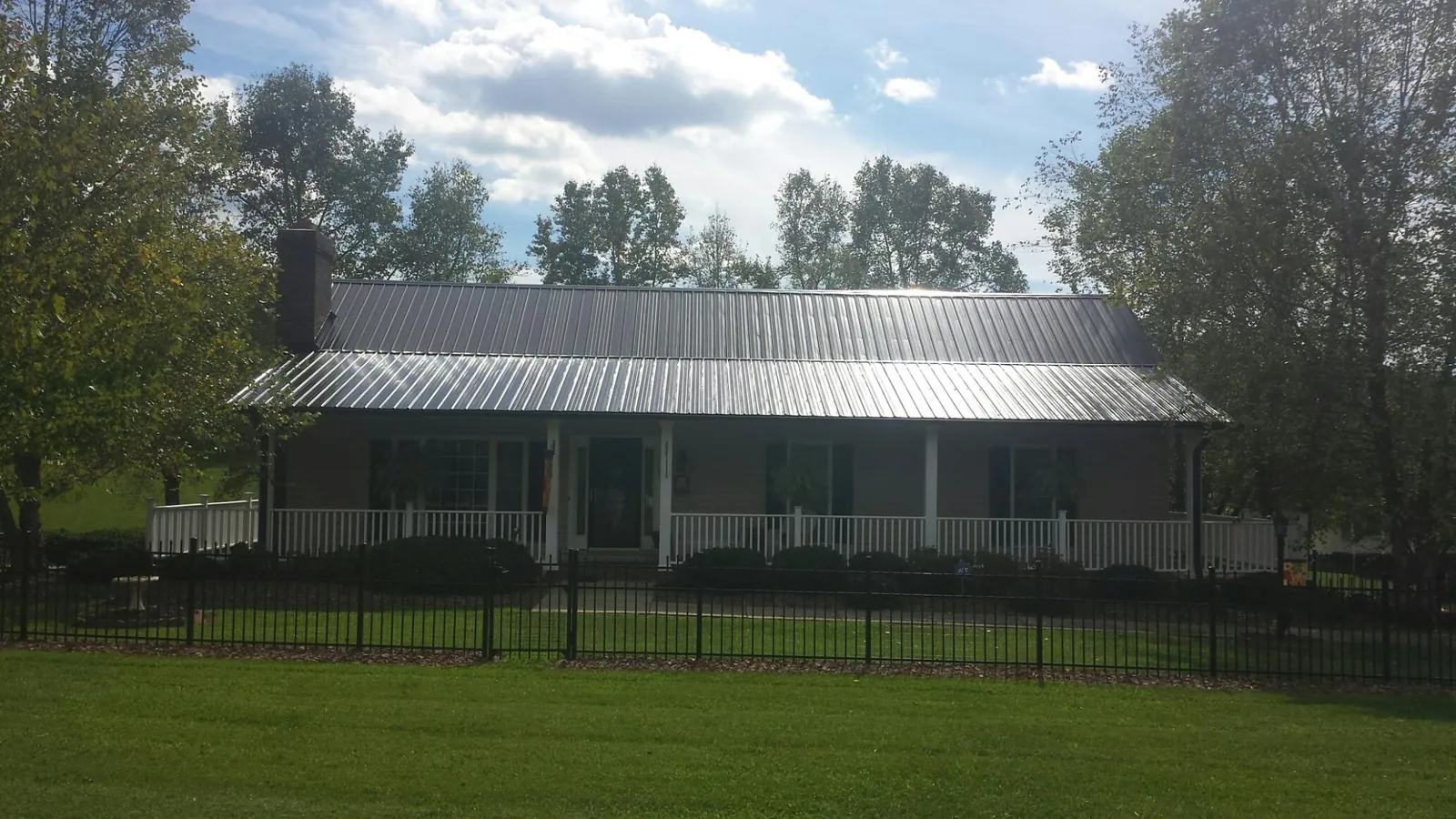 Gray metal roof on a brick ranch with a full width front porch — Gutter Guard Installation work by our crew in Pleasant View