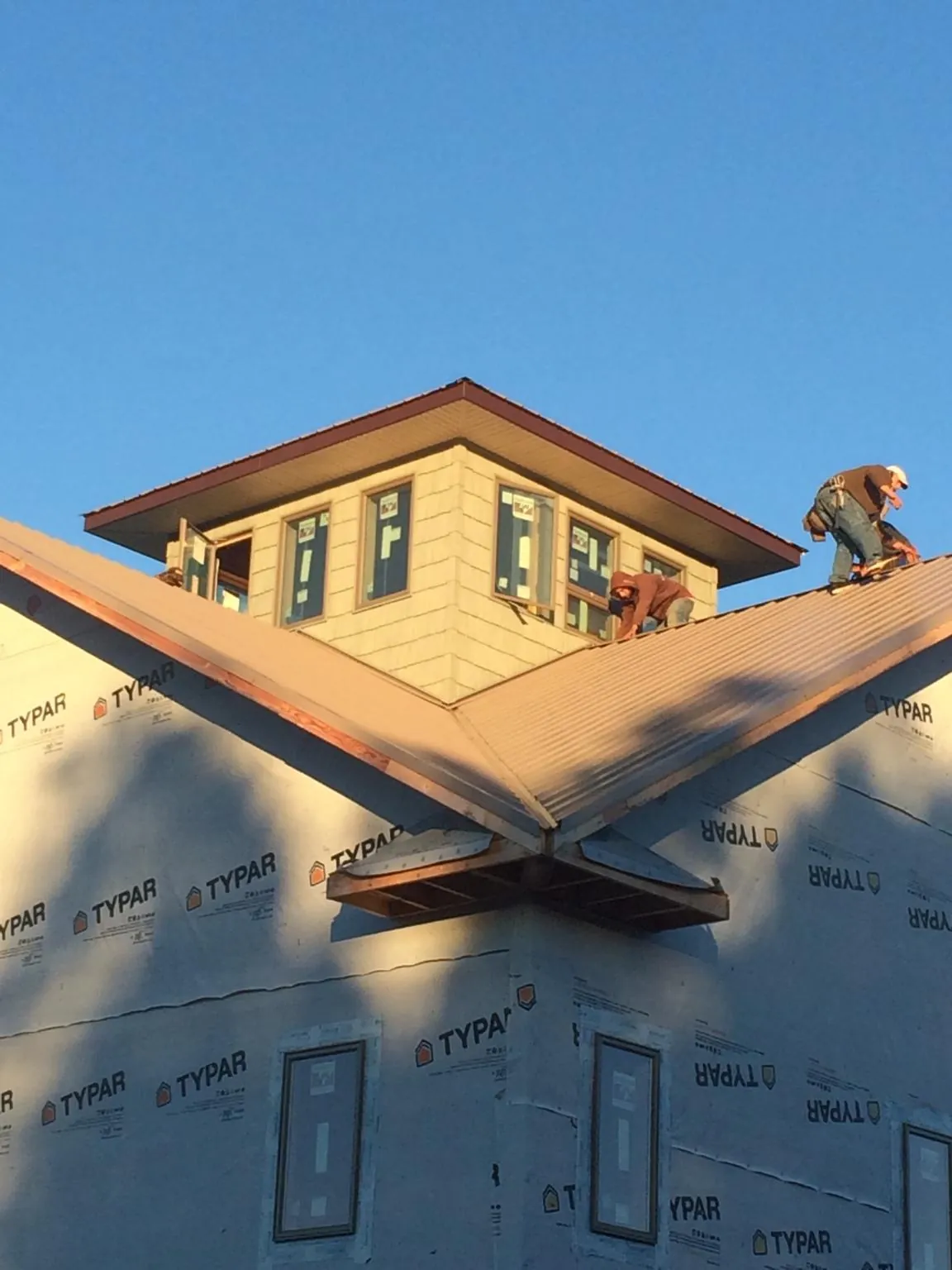 Roofers working around a rooftop cupola on a new metal roof at sunset — Roof Waterproofing in Pleasant View by Roofing Brothers